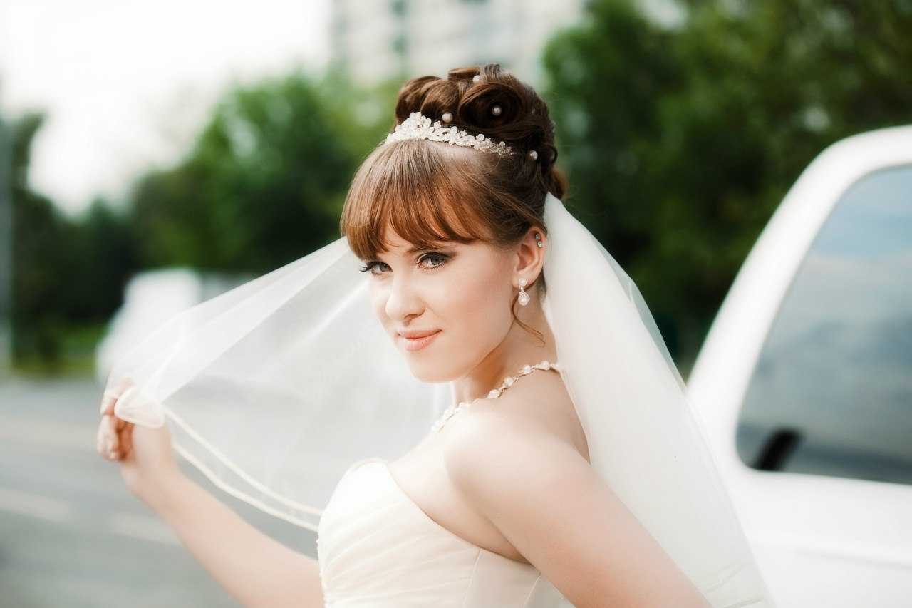 На фото красивые свадебные прически на длинные волосы с фатой шляпкой диадемой челкой а также на волосы средней длины Важность красиво уложенных волос под фатой в свадебном наряде